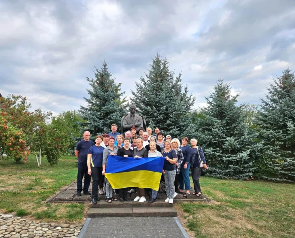 Група людей з українським прапором біля пам’ятника