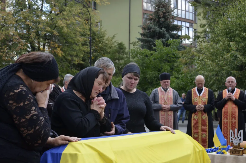 Родина прощається з військовим біля труни з прапором
