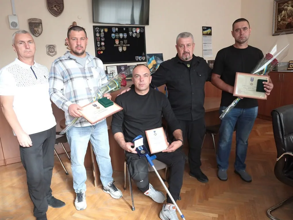 П’ятеро чоловіків з нагородами та квітами в кабінеті