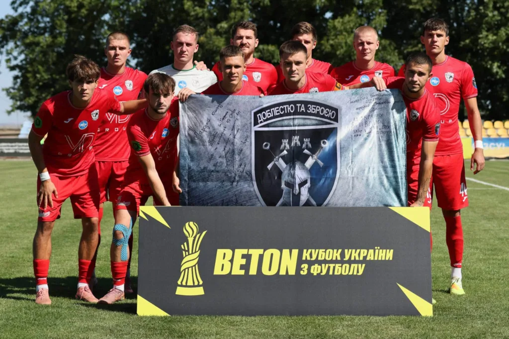 Футбольна команда в червоній формі з банером Кубка України