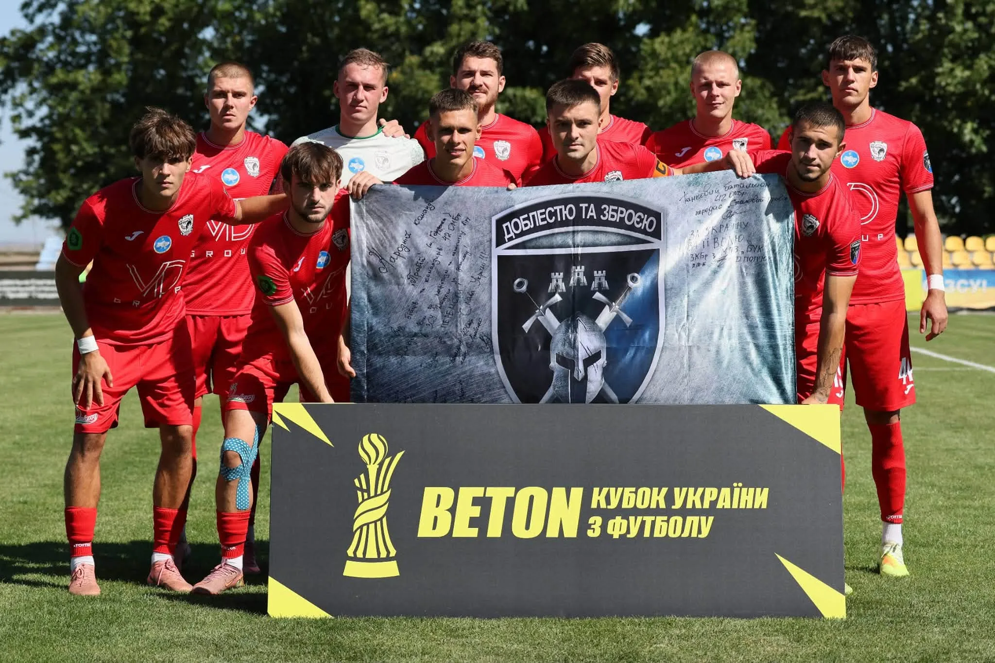 Футбольна команда в червоній формі з банером Кубка України