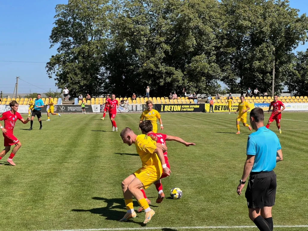 Футболісти в жовтій і червоній формах борються за м’яч