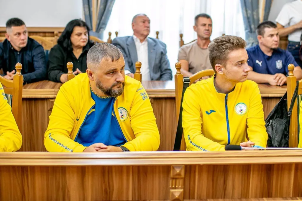Спортсмени у жовтих куртках на офіційному засіданні
