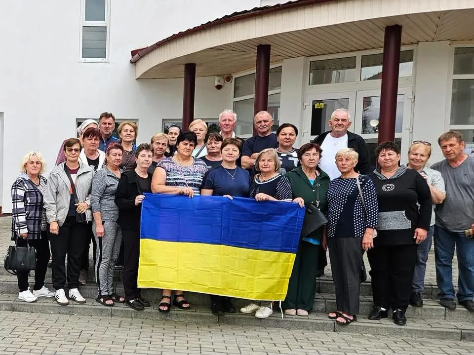 Група людей тримає український прапор біля будівлі