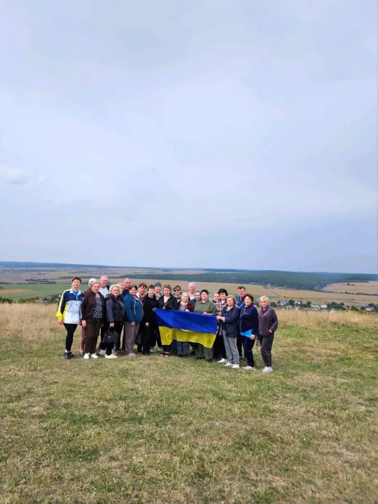 Група людей тримає український прапор на пагорбі