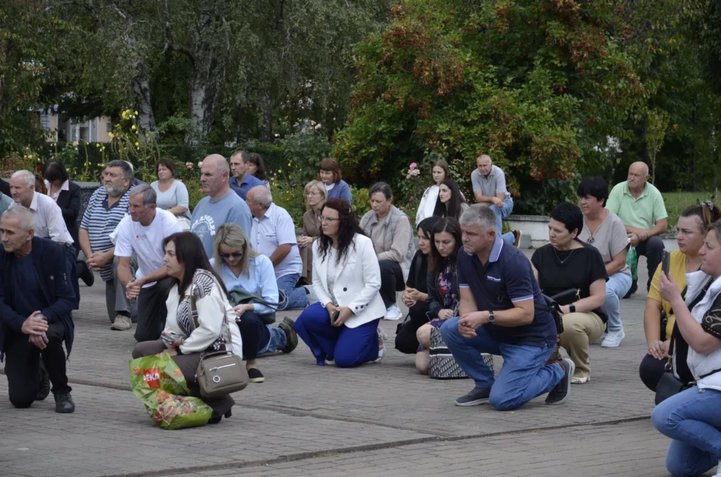 Люди стоять навколішки під час заходу в парку