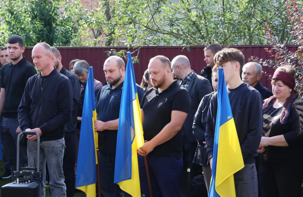 Люди з українськими прапорами на жалобній церемонії