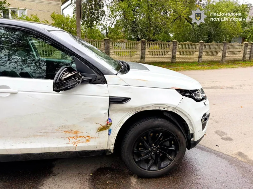 Пошкоджений білий позашляховик на вулиці біля паркану