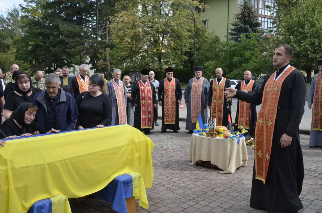 Панахида над труною, вкритою українським прапором