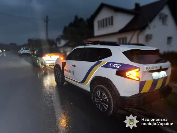 Поліцейські автомобілі на мокрій дорозі вночі