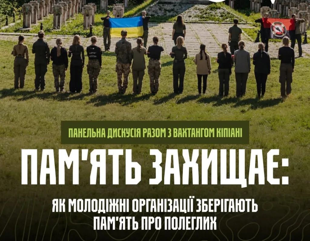 Молодь із прапорами вшановує полеглих на військовому кладовищі