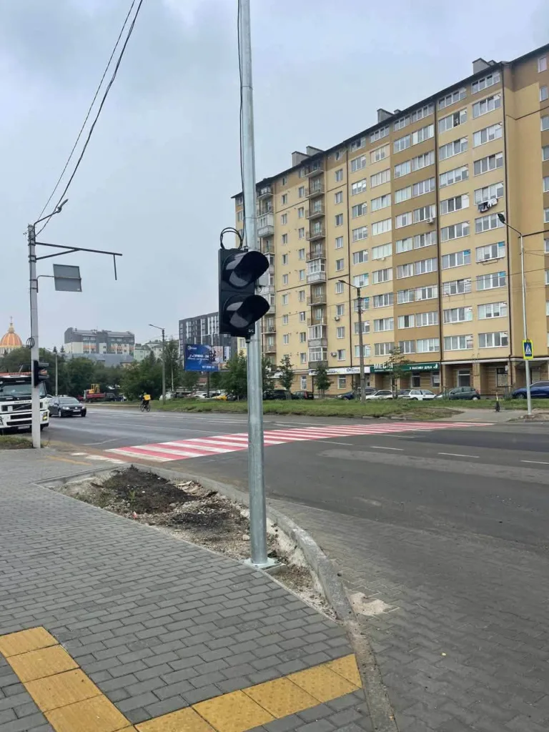 Світлофор біля червоно-білого переходу та житлового будинку