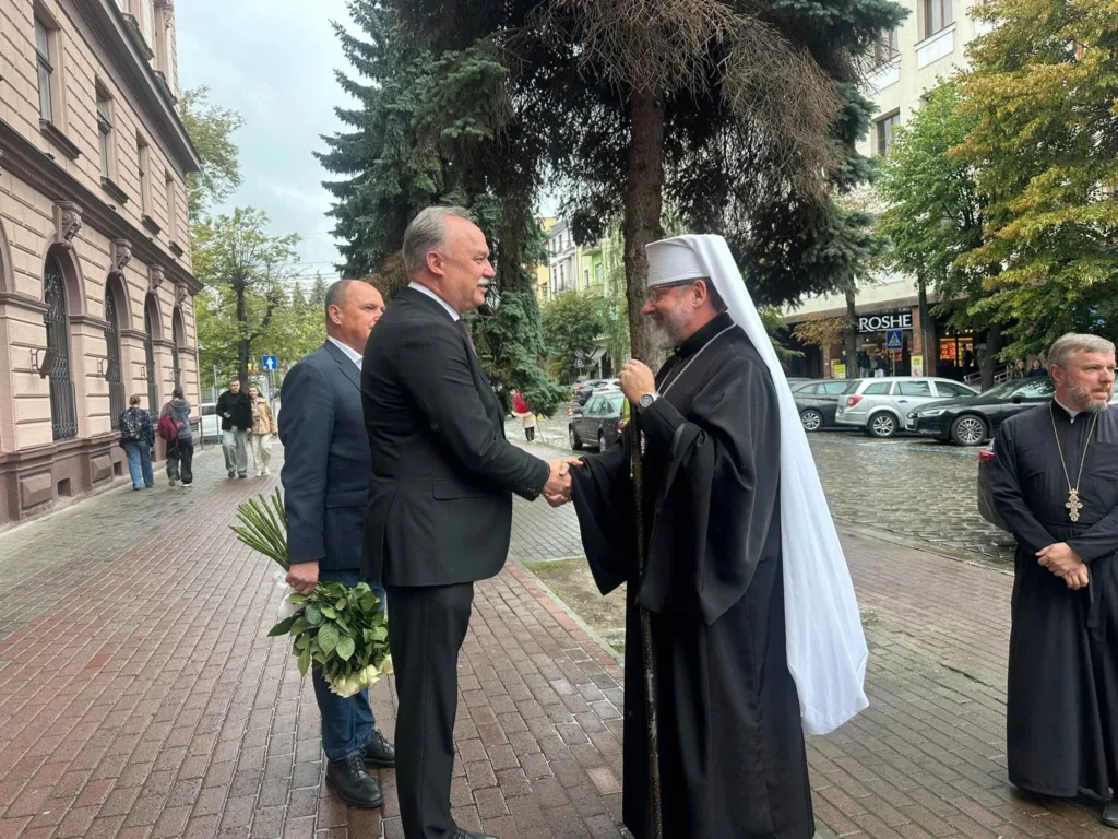 Чоловік тисне руку православному священнослужителю на вулиці