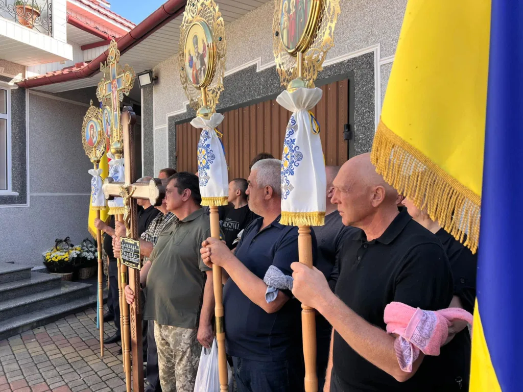 Чоловіки з церковними хоругвами біля храму