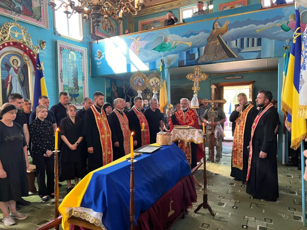 Панахида в українській церкві біля труни, вкритої прапором