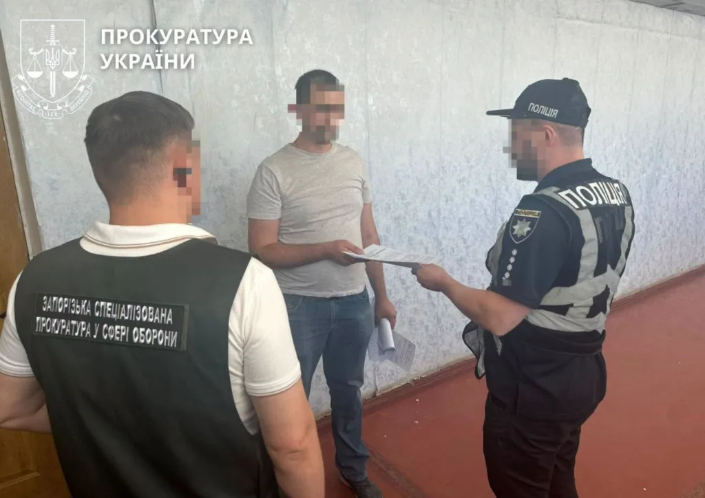 Поліцейський вручає документи чоловікові у присутності прокурора