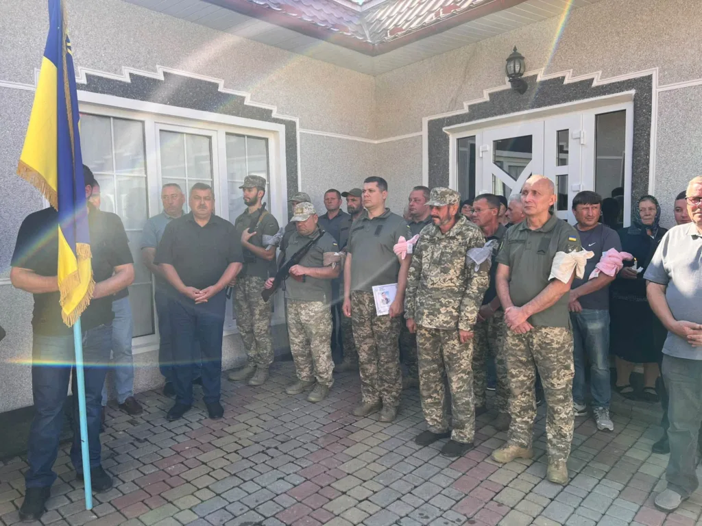 Військові та цивільні біля будівлі з українським прапором