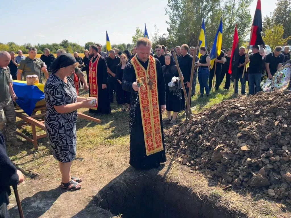 Священник проводить похоронний обряд біля могили військового
