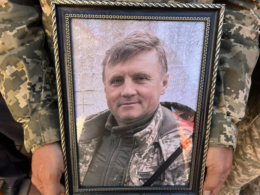 Руки військового тримають портрет загиблого захисника в рамці