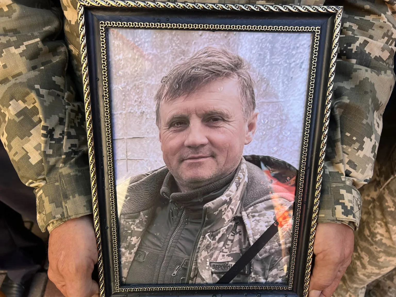Руки військового тримають портрет загиблого захисника в рамці