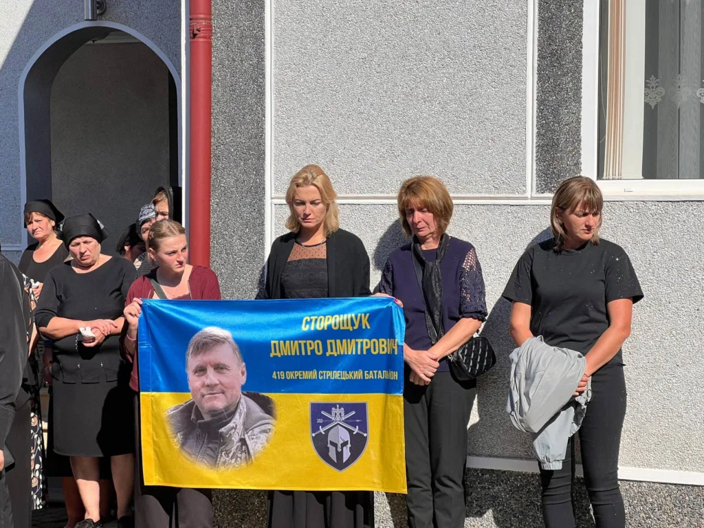 Жінки тримають меморіальний прапор загиблого військового