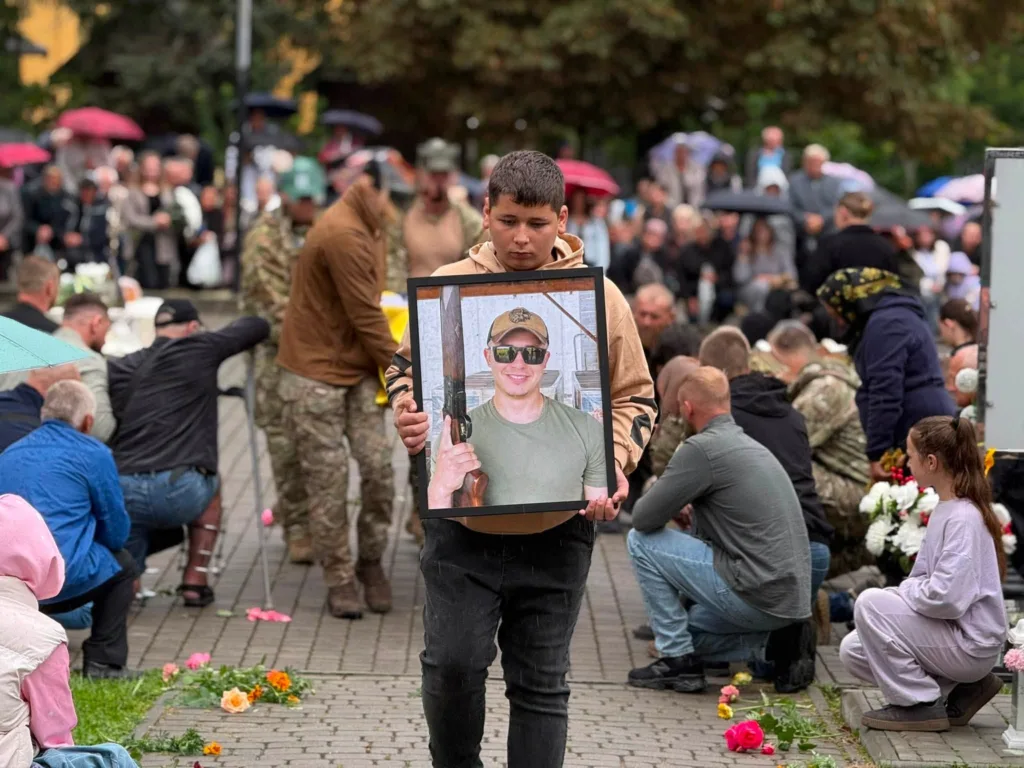 Хлопець тримає портрет військового на похороні