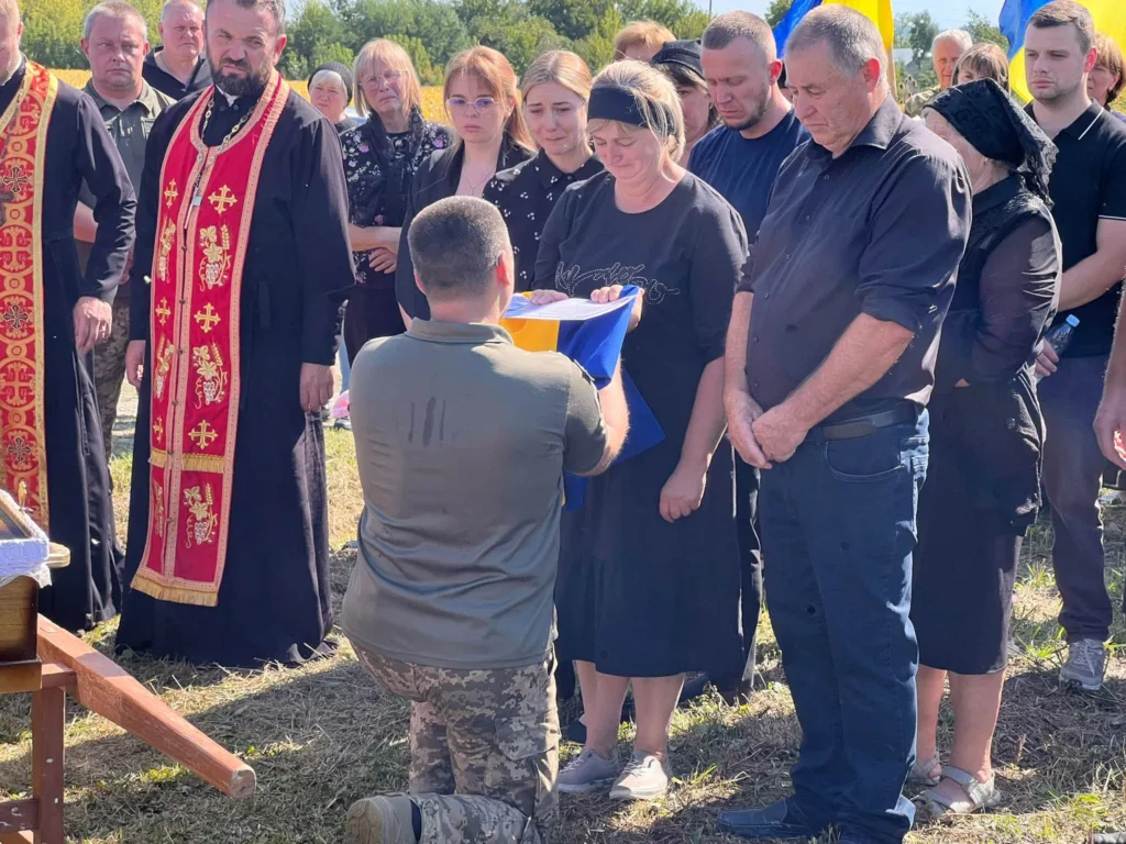 Військовий передає прапор родині на похороні