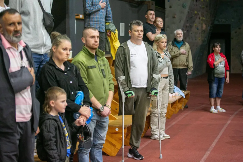 Люди стоять із руками на серці, ветеран на милицях