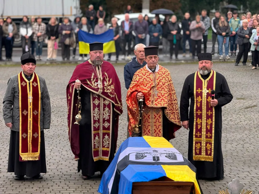 Священники проводжають загиблого воїна з українським прапором