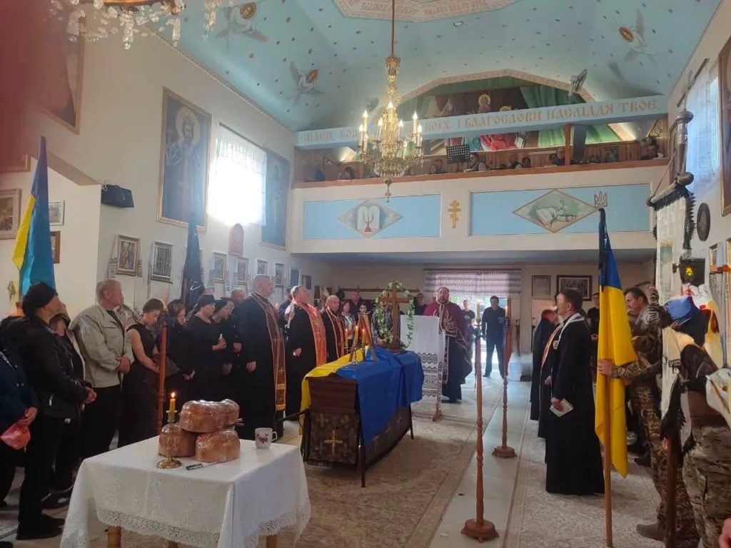 Похоронна служба за військовим у храмі з українськими прапорами