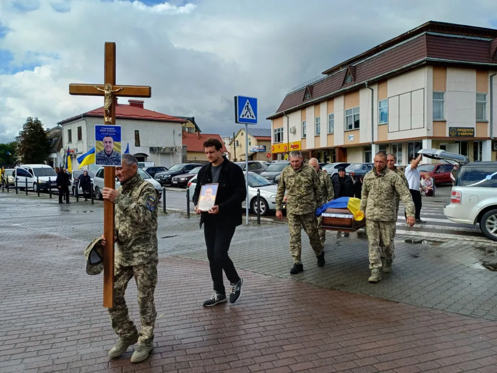 Військові несуть труну героя під українським прапором