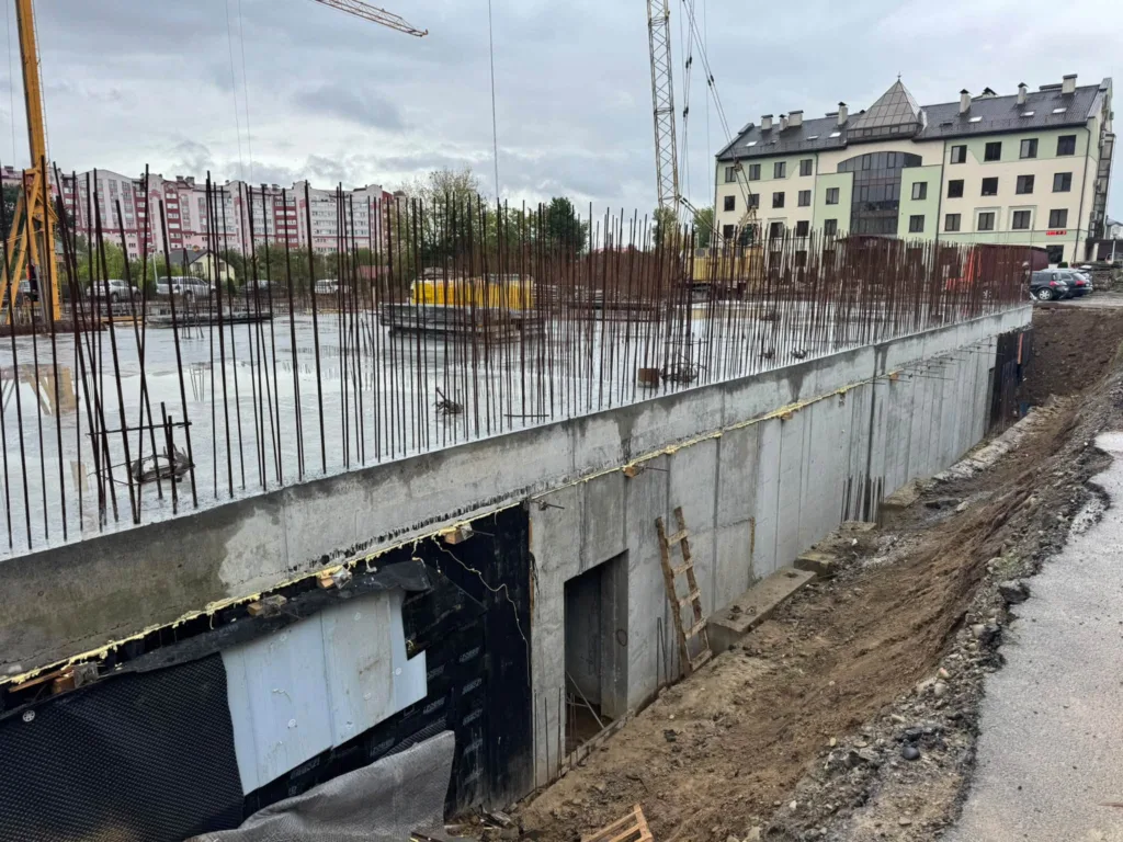 Будівництво фундаменту багатоповерхівки з арматурою та кранами
