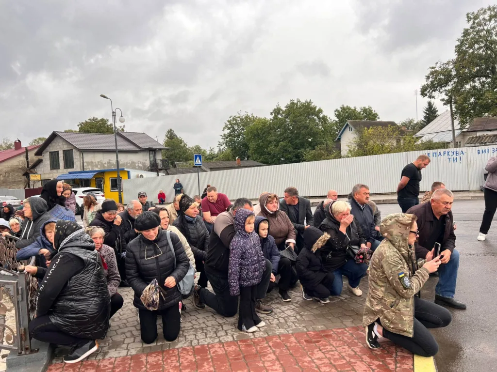Люди навколішки на вулиці під похмурим небом