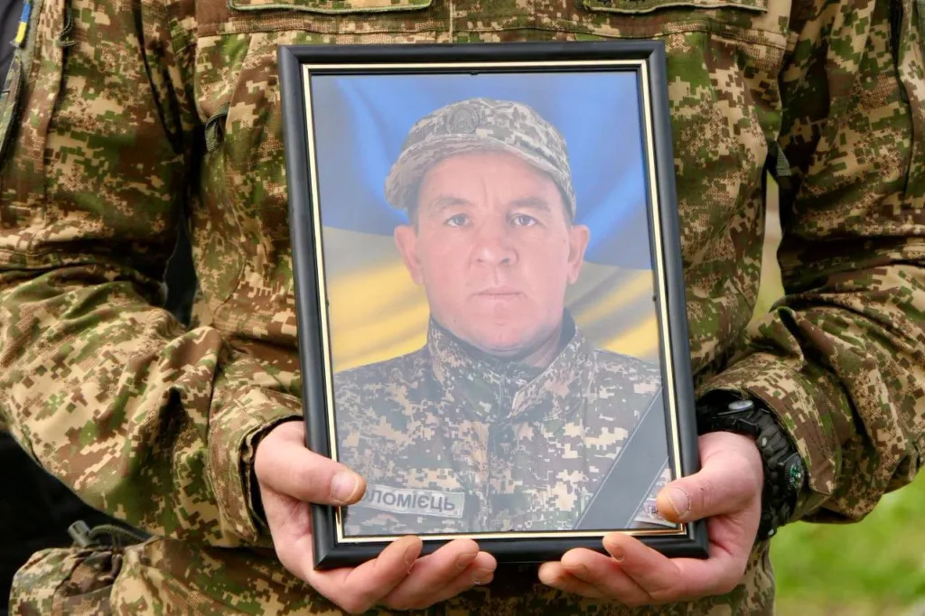 Військовий тримає портрет загиблого захисника України