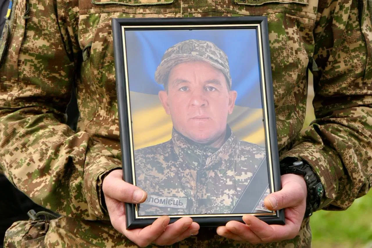 Військовий тримає портрет загиблого захисника України