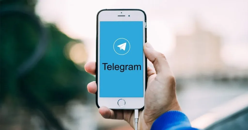 Рука тримає смартфон із логотипом Telegram на екрані