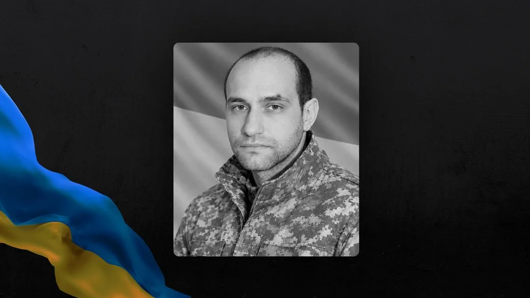 Чорно-білий портрет військового на тлі українського прапора