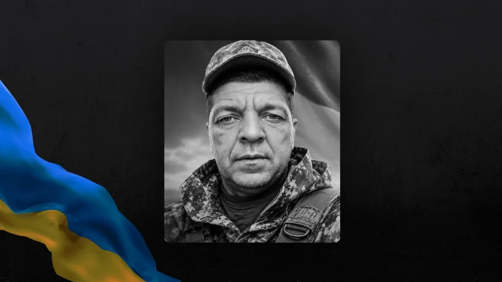 Чорно-білий портрет українського військового на тлі прапора