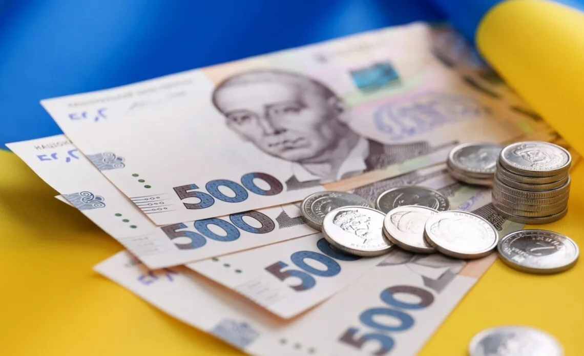 Українські гривні та монети на синьо-жовтому тлі