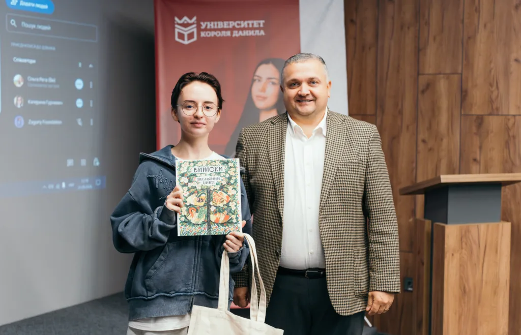Двоє людей за склом, жінка тримає ілюстровану книжку