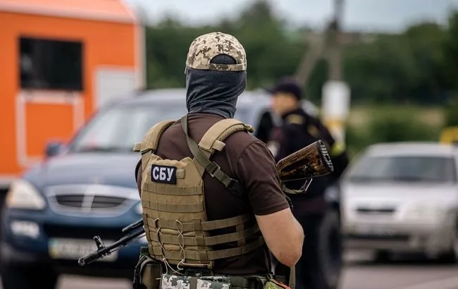 Співробітник СБУ зі зброєю біля автомобілів