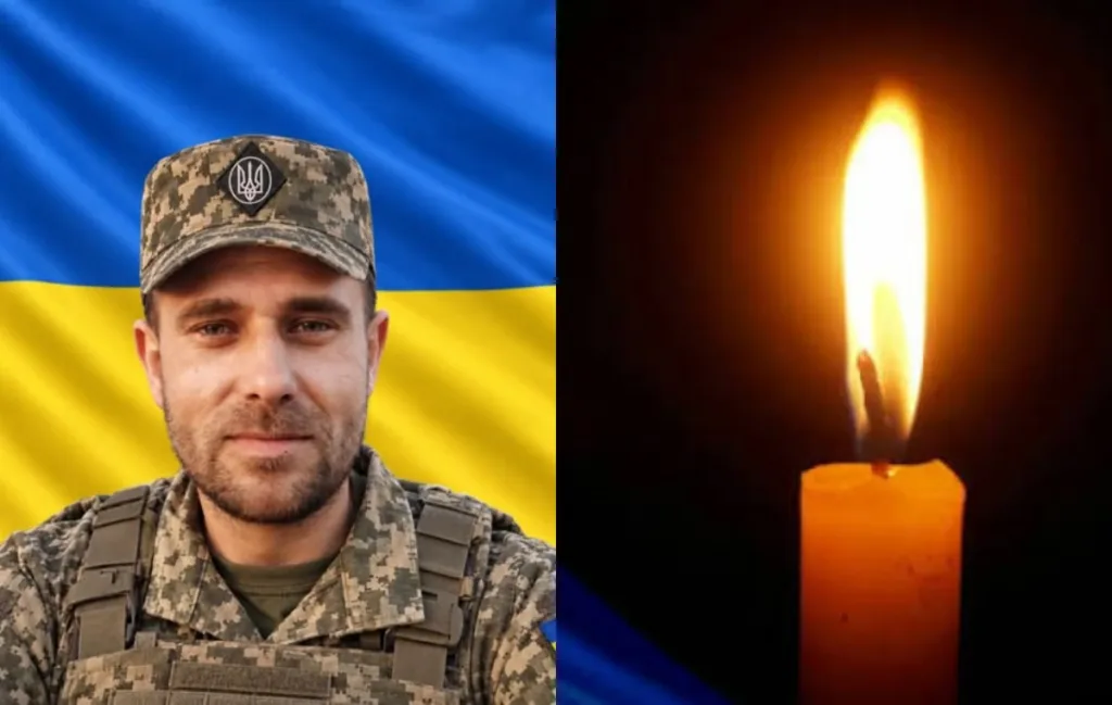 Український військовий на тлі прапора і запалена свічка
