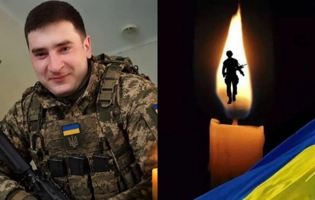 Український військовий поруч із меморіальною свічкою та прапором
