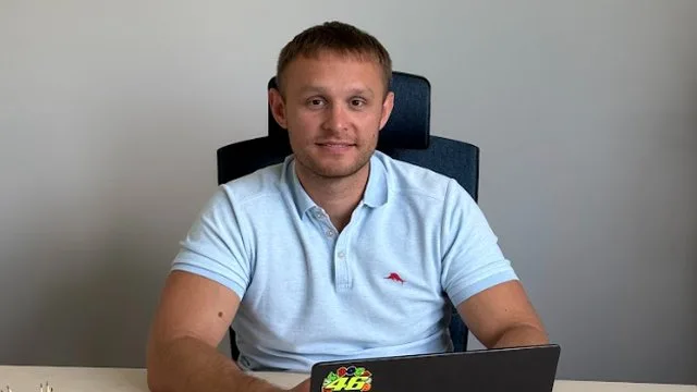Чоловік у блакитному поло сидить за ноутбуком