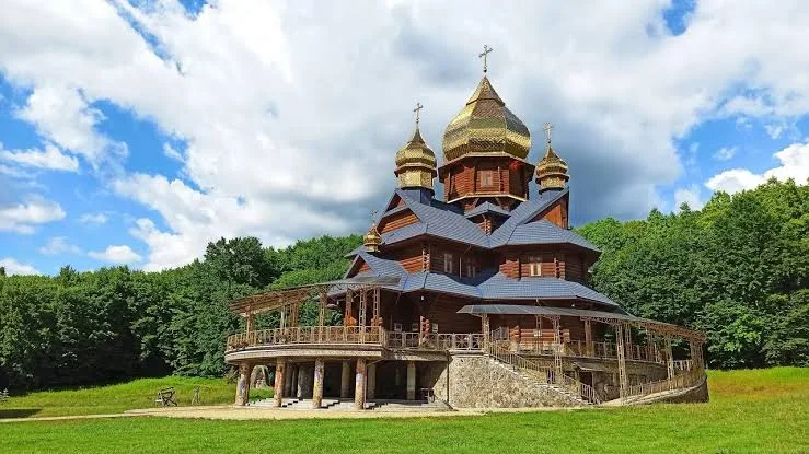 Дерев’яна церква з золотими банями серед зелені