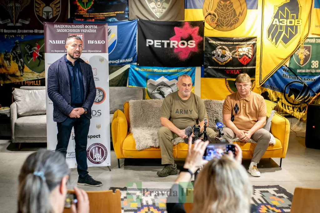 Учасники форуму захисників України на тлі військових прапорів