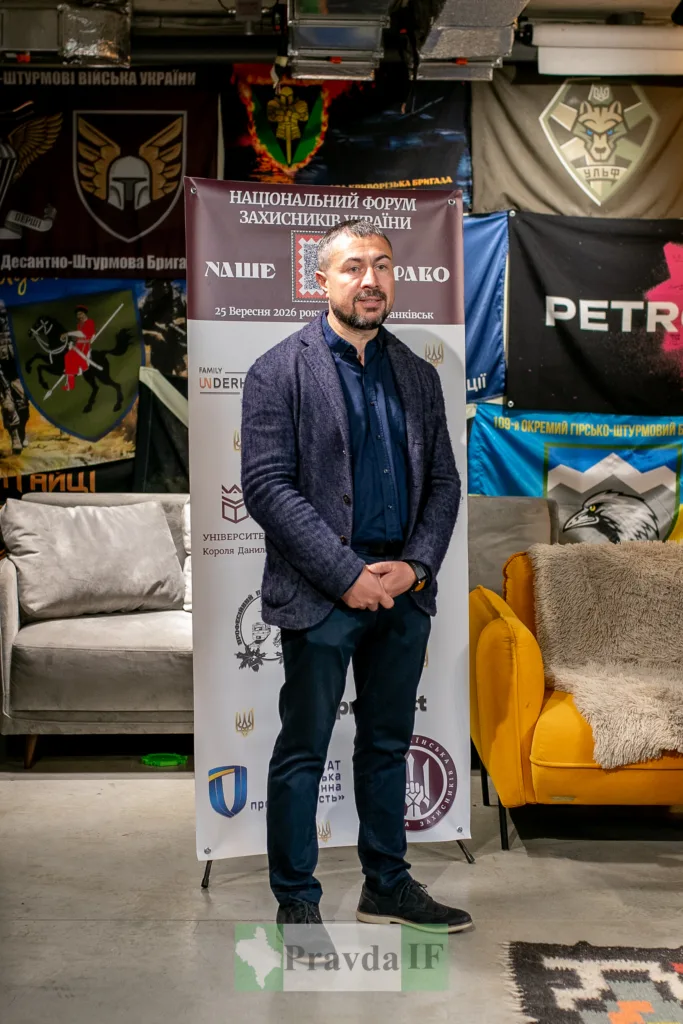 Чоловік на форумі захисників України біля військових прапорів