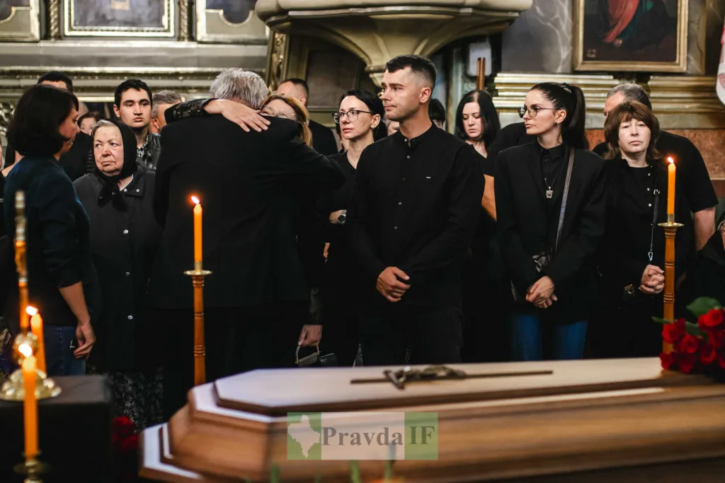 Люди прощаються біля труни зі свічками в храмі