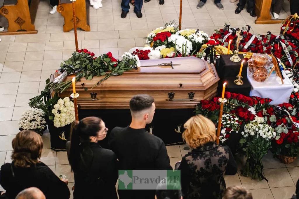 Труна з квітами й свічками під час похорону