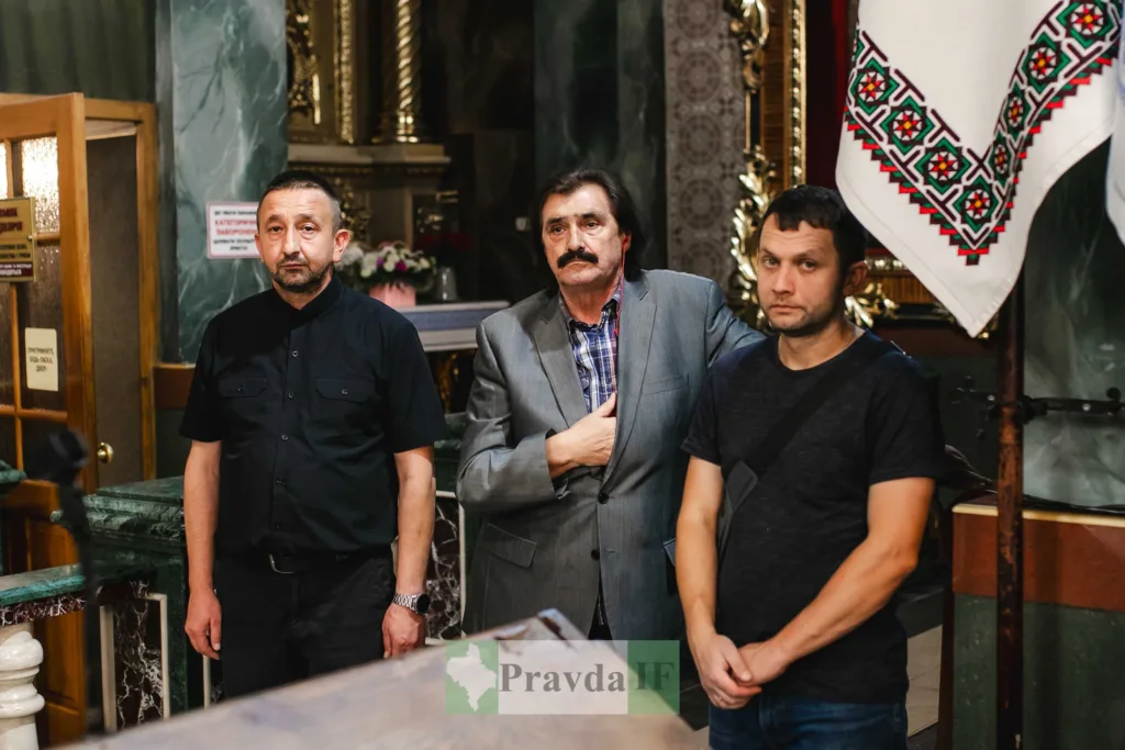 Троє чоловіків у храмі біля вишитого рушника